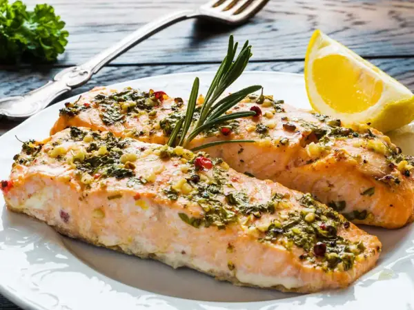 Två saftiga laxfiléer med en härlig pesto-topping, garnerade med rosmarin och en citronklyfta.
