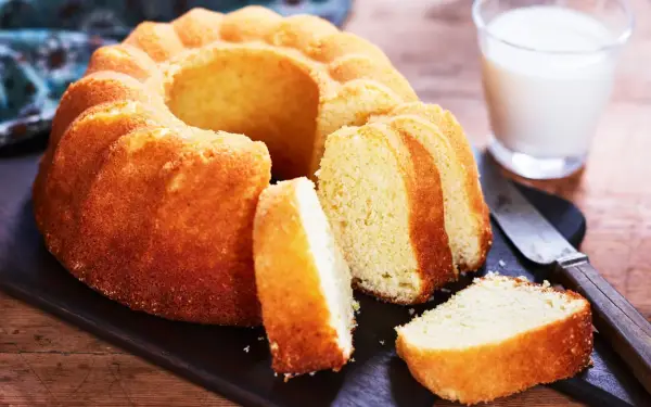 En gyllene sockerkaka, perfekt för ett enkelt sockerkaka recept. Serveras med ett glas mjölk och en kniv.