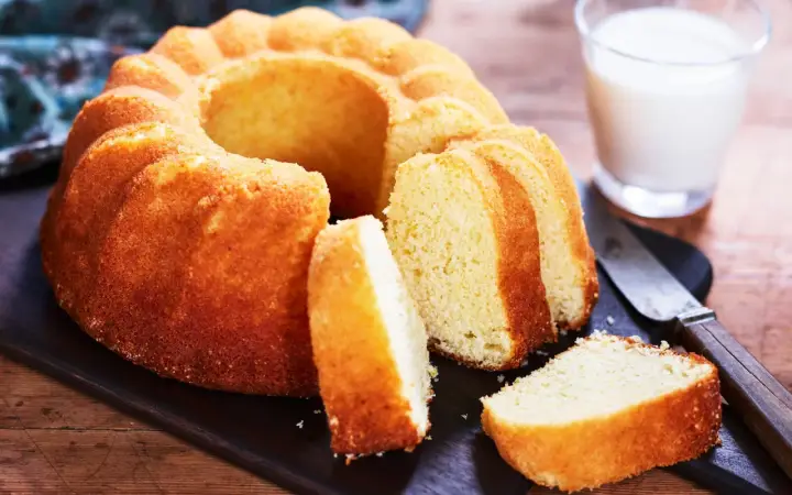 En gyllene sockerkaka, perfekt för ett enkelt sockerkaka recept. Serveras med ett glas mjölk och en kniv.